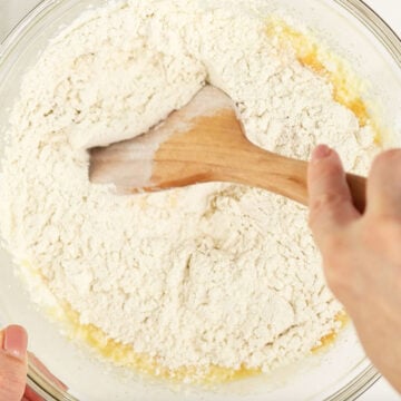 Dry mixture being mixed into the wet mixture with a wooden spoon. 