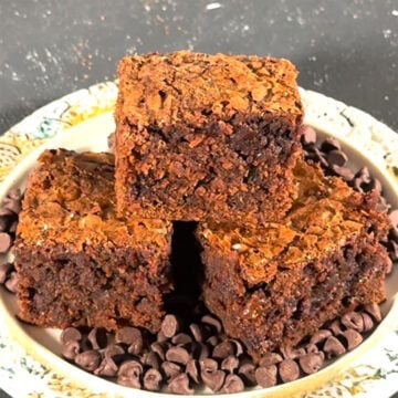 Slices of fudgy brownies stacked on top of each other on a rustic dish. 