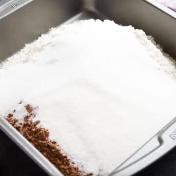 Flour, sugar and cocoa powder in a square cake pan. 