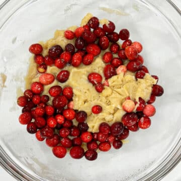 Fresh cranberries added to batter in glass bowl.  