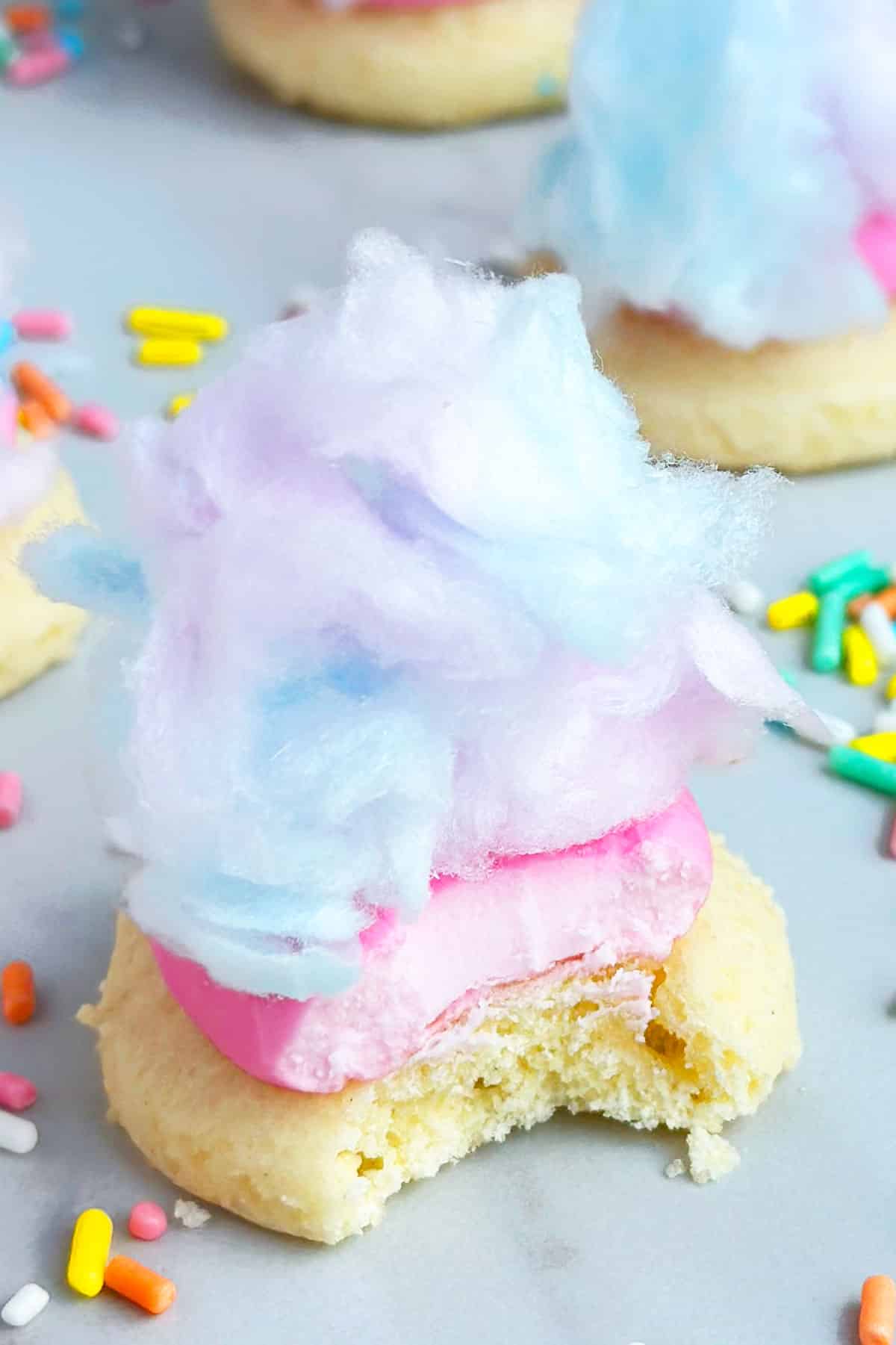 Partially Eaten Sugar Cookie With Frosting and Candy on White Marble Background.