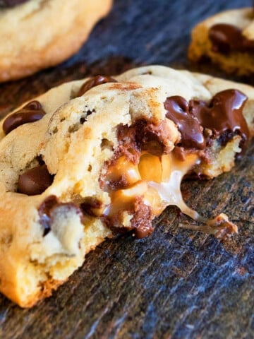 Easy Stuffed Salted Caramel Chocolate Chip Cookies That Are Partially Eaten on Rustic Background.