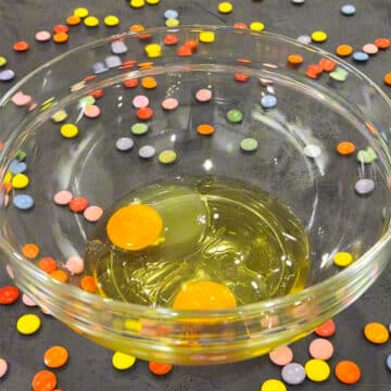 Eggs and oil in glass bowl on black stone background. 