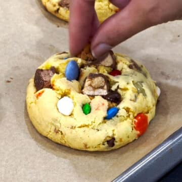 Chopped candies being added to top of baked cookies. 