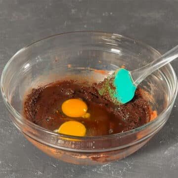 Large glass bowl with melted chocolate mixture, eggs and vanilla extract. 