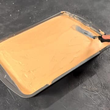 Icing being spread on top of cake with spatula. 