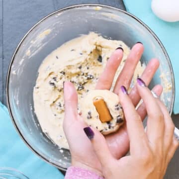 Cookie dough ball being filled with caramel. 