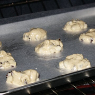 Spoonful of cookie dough on lined baking tray. 