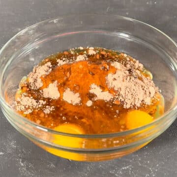 Brownie batter ingredients mixed in large glass bowl. 