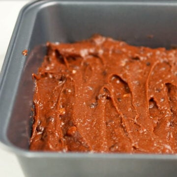 Brownie batter being spread in a baking pan. 