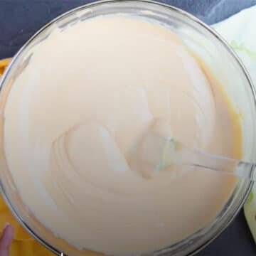 Peanut butter and white chocolate chips melted and mixed together smoothly in glass bowl. 