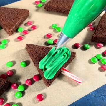 Green frosting being piped on top of brownie. 