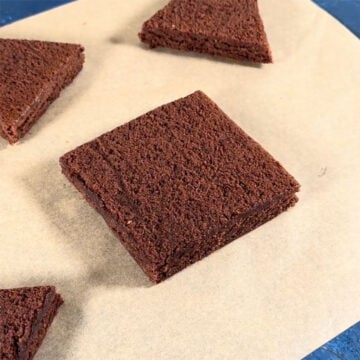 Square slice of brownie on brown parchment paper. 