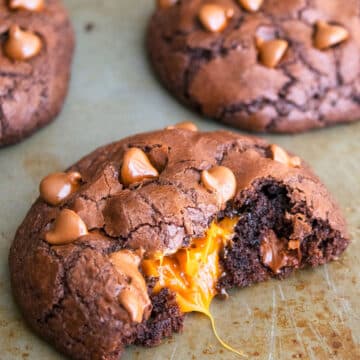 Easy Chocolate Caramel Cookies With Filling Oozing Out on Baking Tray.