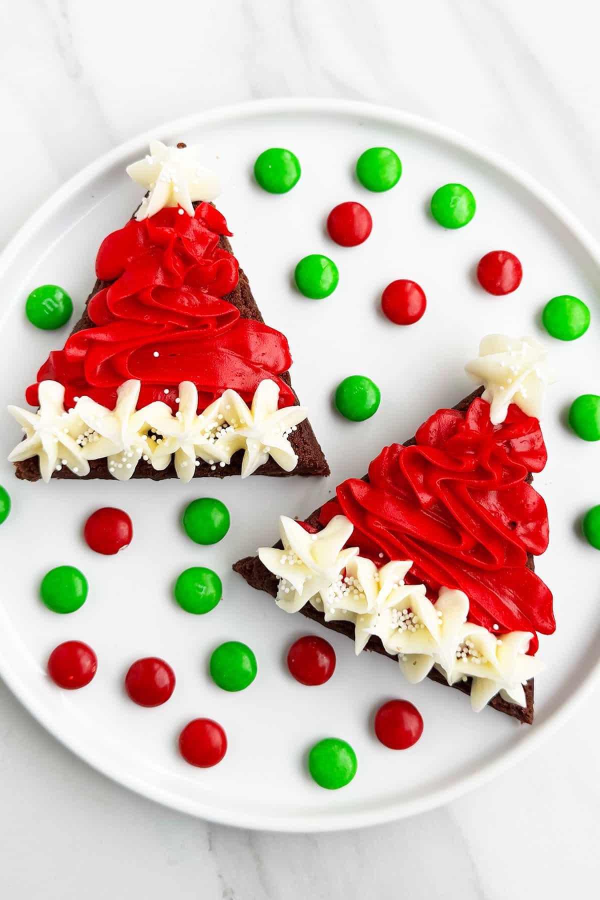 Easy Christmas Santa Claus Brownies Bites With Red and White Buttercream Frosting on White Dish With M&M Candies. 