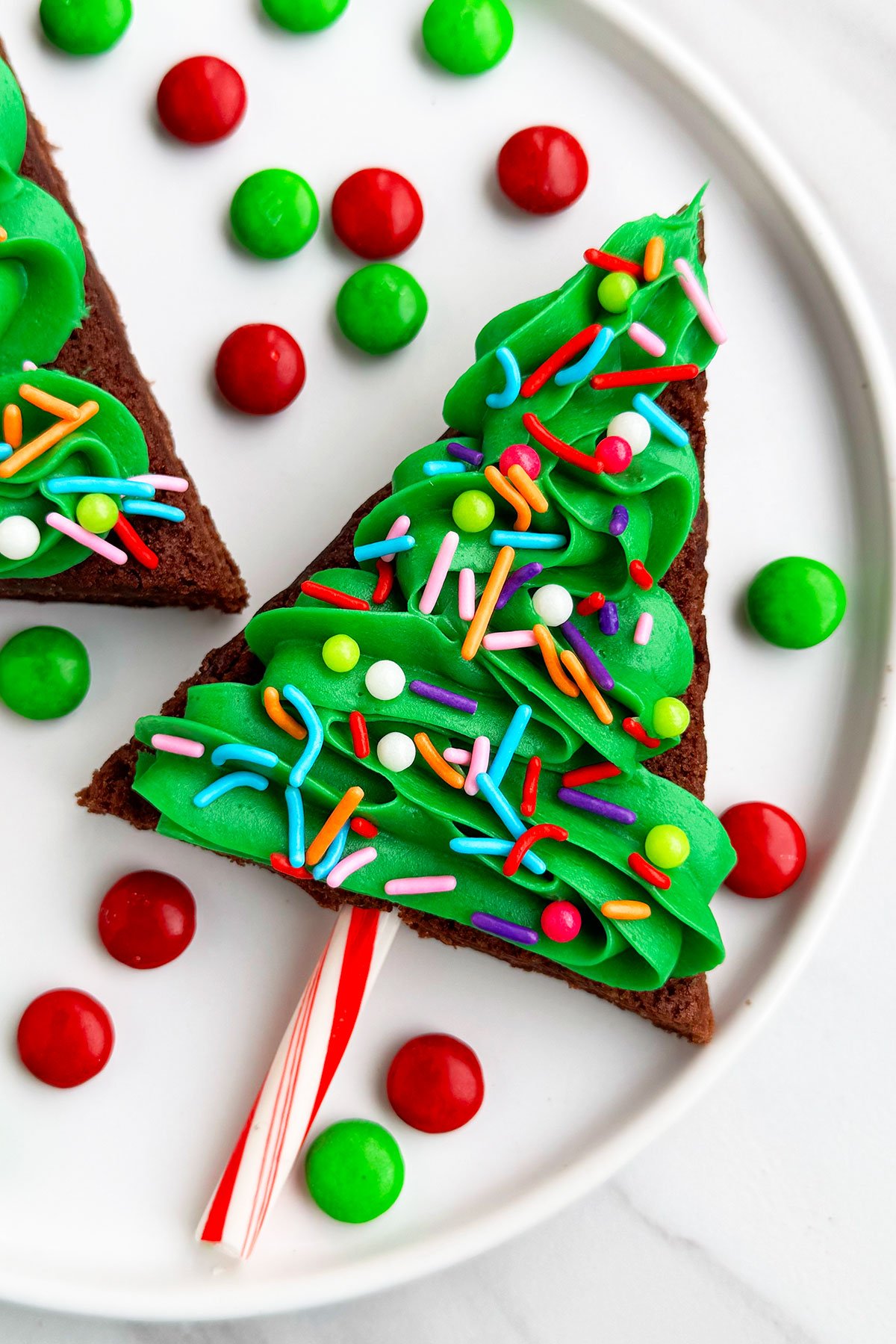 Easy Christmas Tree Brownies With Buttercream Frosting and Sprinkles on White Dish.