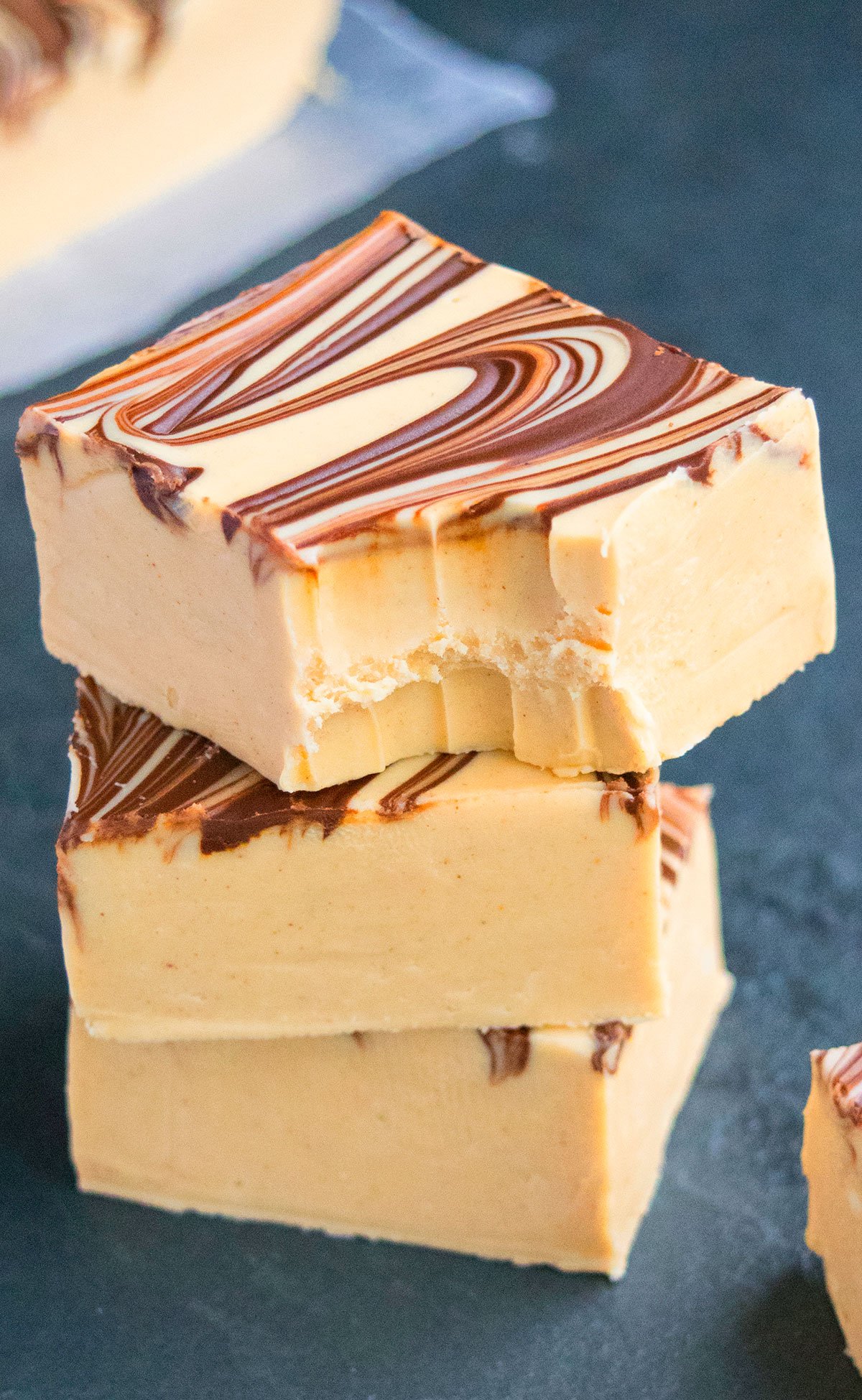 Stack of Fudge Slices With One on Top That's Partially Eaten on Dark Gray Background. 