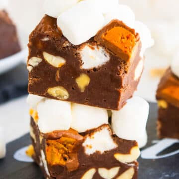 Stack of Rocky Road Fudge Slices on Black Dish With Off White Background.