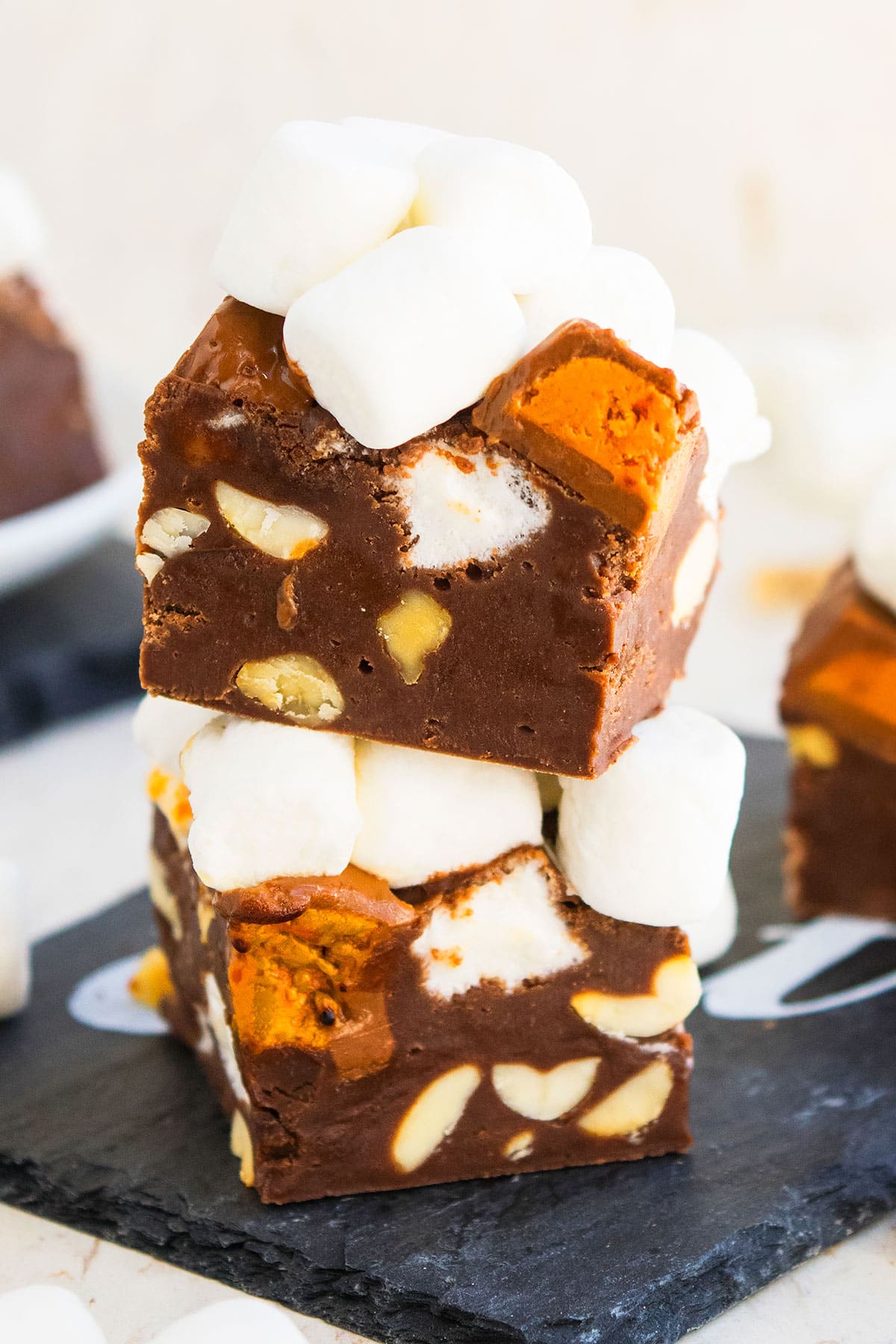 Stack of Rocky Road Fudge Slices on Black Dish With Off White Background. 