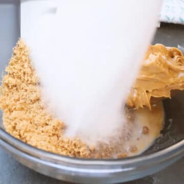 Glass bowl with coconut oil, peanut butter, vanilla extract, milk, brown sugar, granulated sugar.