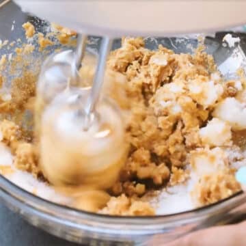 Ingredients being mixed in a glass bowl with hand mixer. 