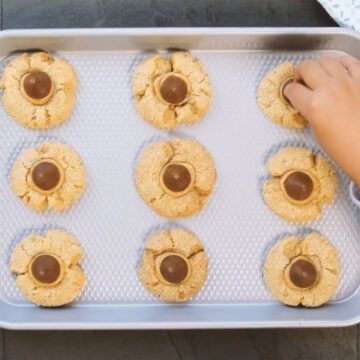 Baked cookies being filled with peanut butter and chocolate. 