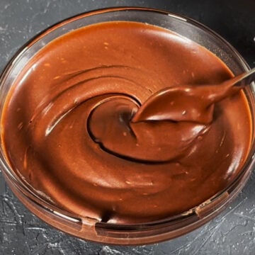 Smooth cocoa mixture in glass bowl with spoon. 