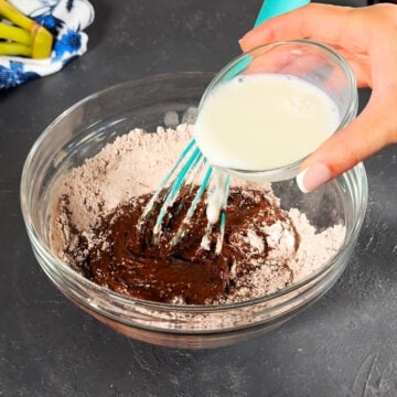 Additional milk being added to cocoa mixture in glass bowl. 