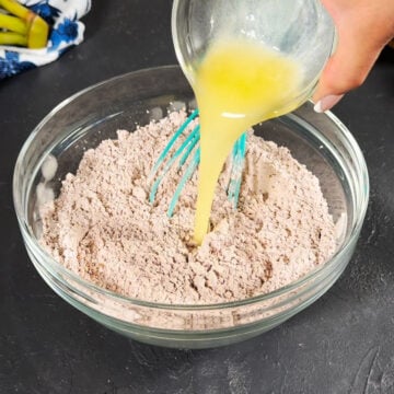 Melted butter being added to dry mixture in glass bowl. 