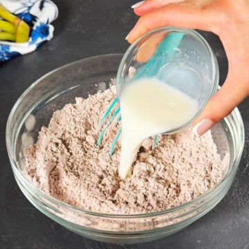 Milk being added to dry mixture in glass bowl. 