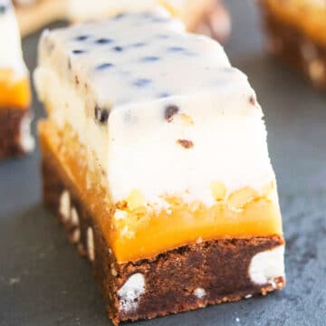 Slices of Chocolate Cookie Bars With 5 Layers on Black Stone Background.