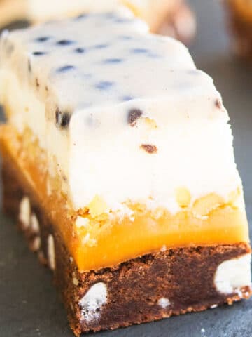 Slices of Chocolate Cookie Bars With 5 Layers on Black Stone Background.