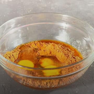 Cocoa powder, eggs and brewed coffee in glass mixing bowl.