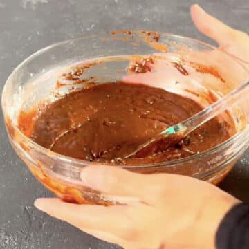 Brownie batter in glass bowl with spatula. 