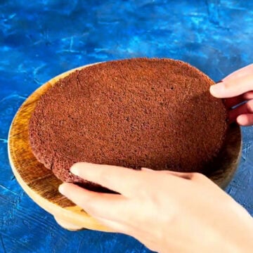 Round brownie being placed on a cake stand. 