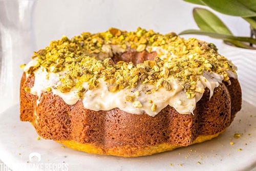 Bundt with glaze and chopped pistachios on white dish.