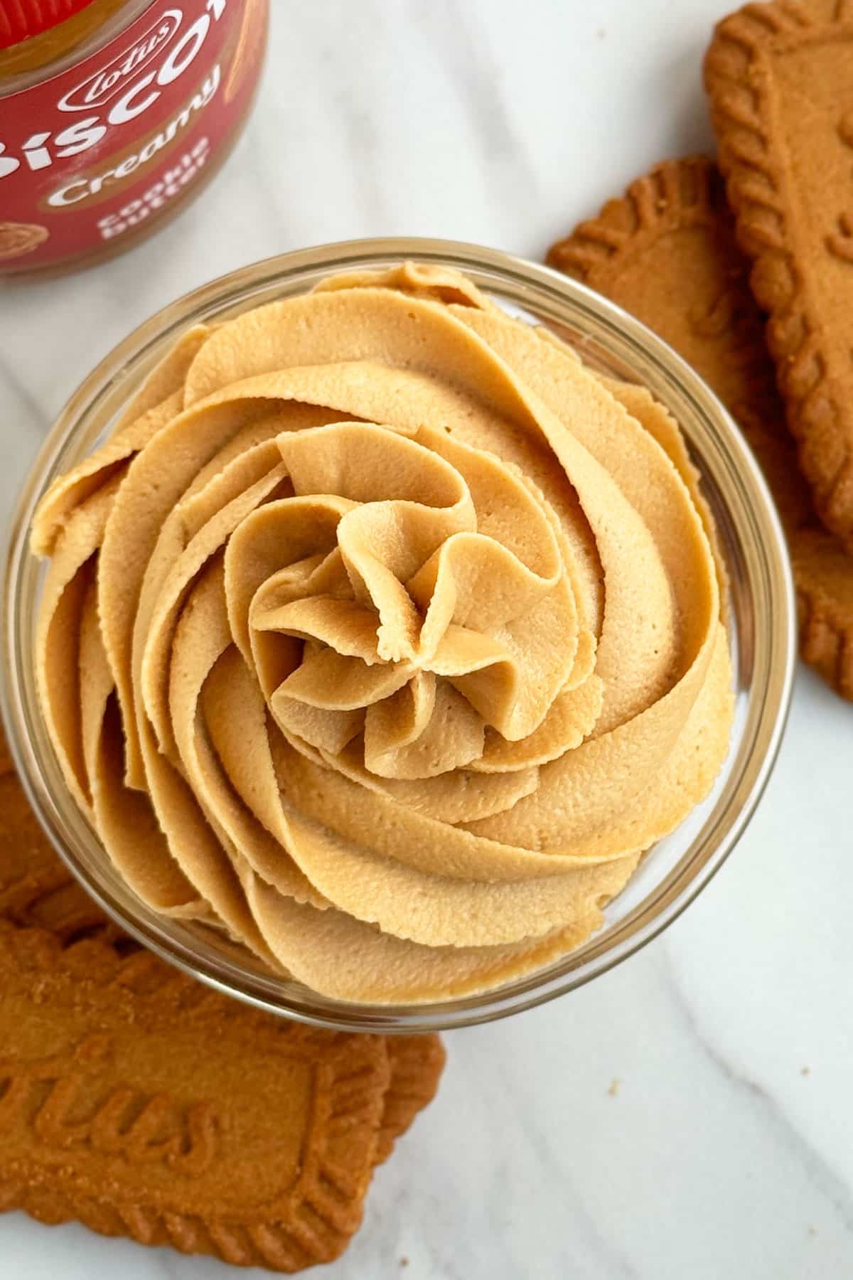 Cookie Butter Frosting in Glass Bowl on White Marble Background. 