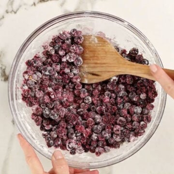 Wooden spoon being used to mix ingredients together in glass bowl. 