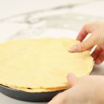 Pie crust being spread over the filling. 