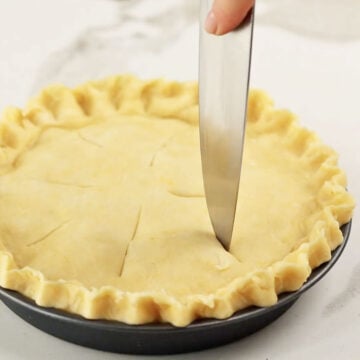 Knife being used to make cuts for venting on top of pie crust. 