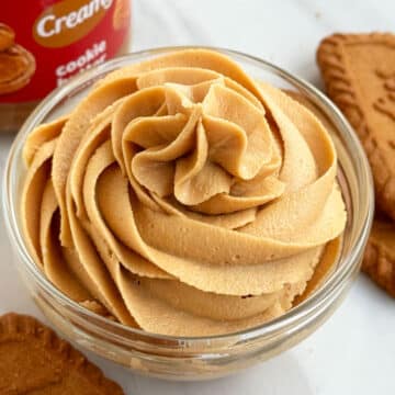 Glass Bowl of Biscoff Frosting on White Marble Background.