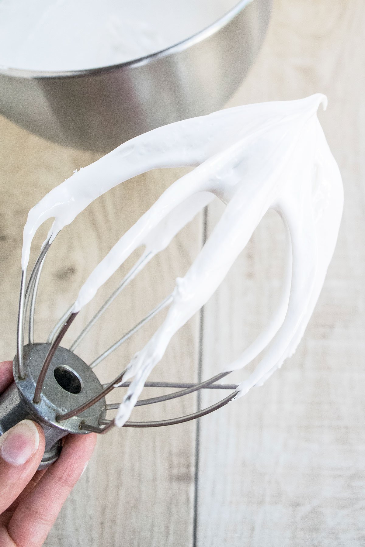 Whisk With Easy Seven Minute Frosting on Light Brown Background.