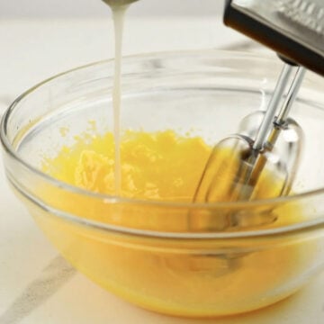 Egg yolks being tempered in glass bowl. 