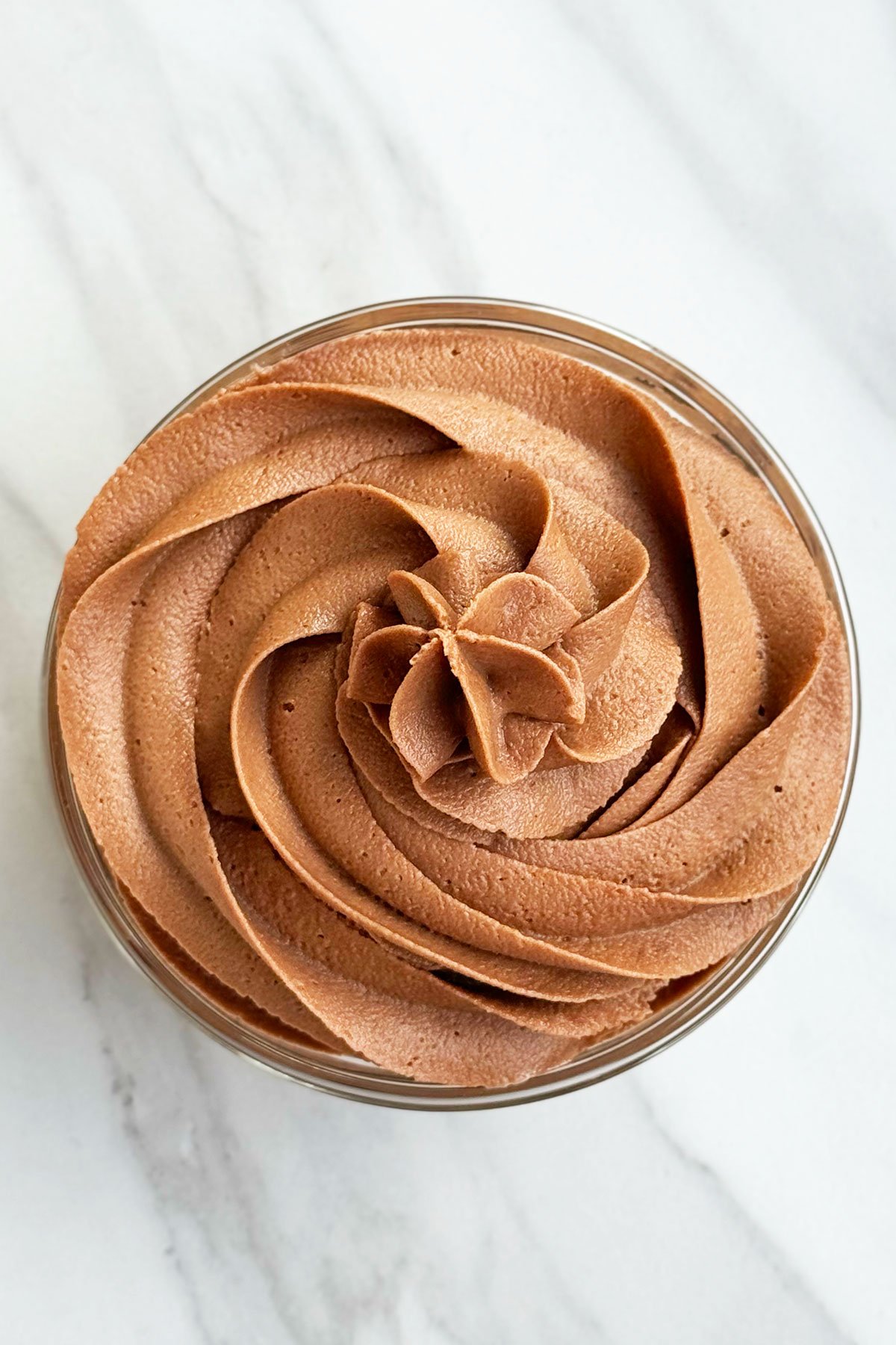 Overhead Shot of Swirl of Chocolate Hazelnut Icing on White Marble Background. 