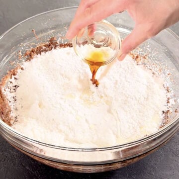 Vanilla extract being added to glass bowl. 