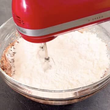 More powdered sugar added to glass bowl. 