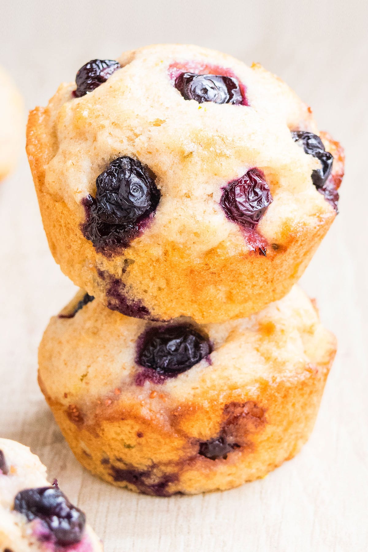 Stack of Soft Lemon Blueberry Muffins on Light Brown Background.