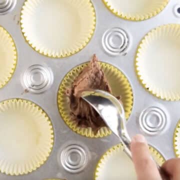 Adding spoonful of batter in cupcake liner. 