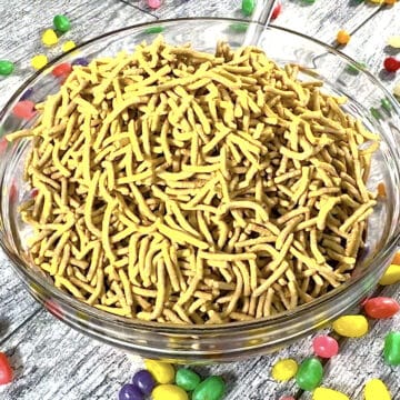 Chow mein noodles added to chocolate mixture in glass bowl. 