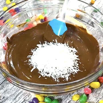 Shredded coconut added to chocolate mixture in glass bowl. 